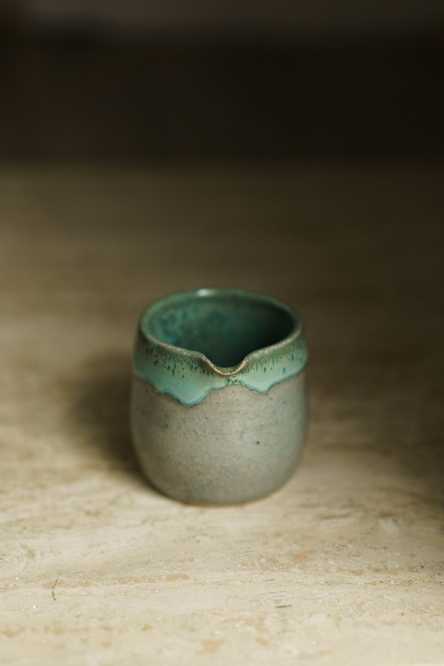 Small spouted beaker in a transparent glaze with light blue/green glaze inside and on the rim.