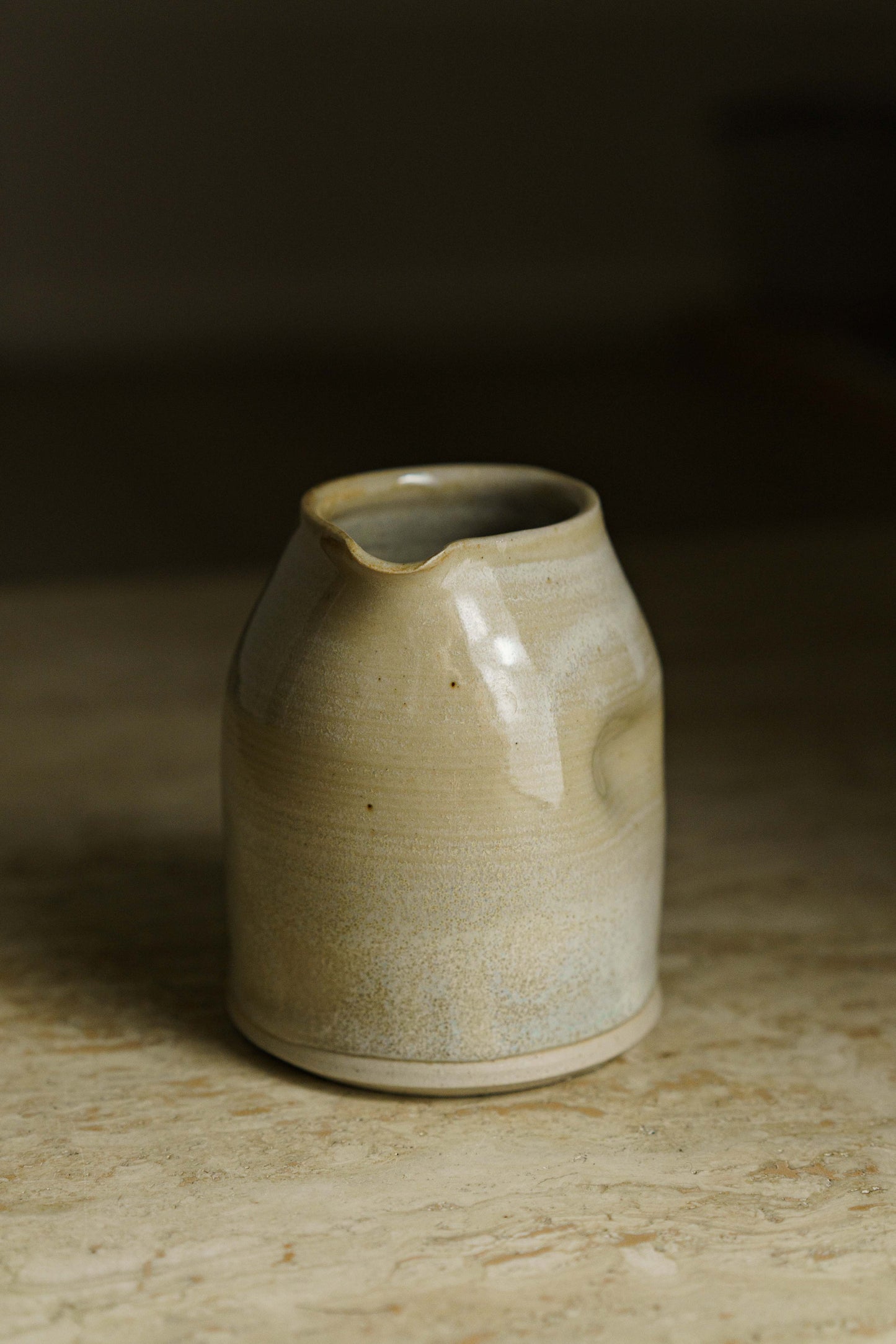 Cream colored spouted pourer with finger indent on the side.