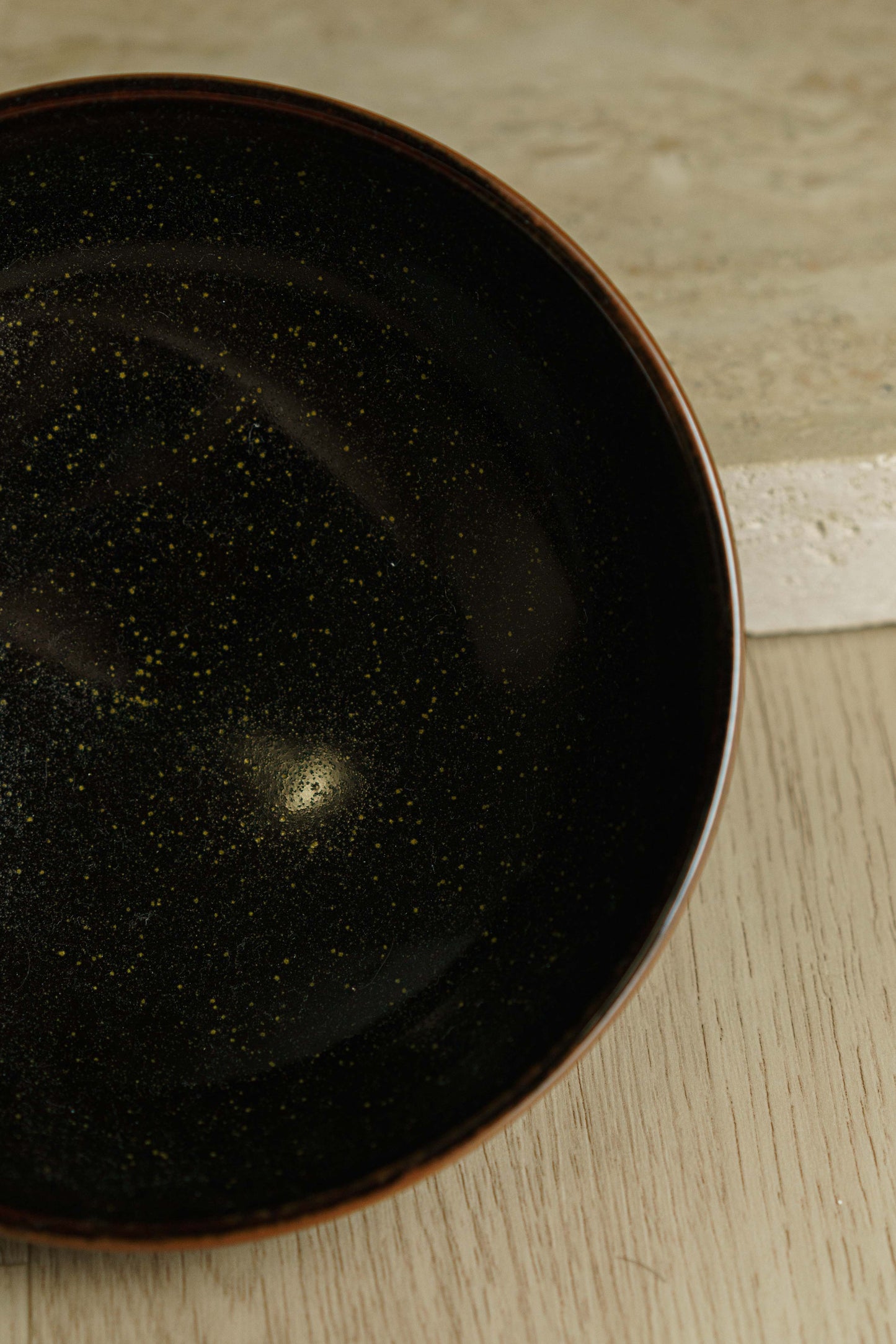 Black bowl with green flecks and angular outer wall.