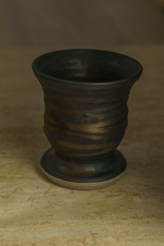 Black pedestal vase with copper lines.