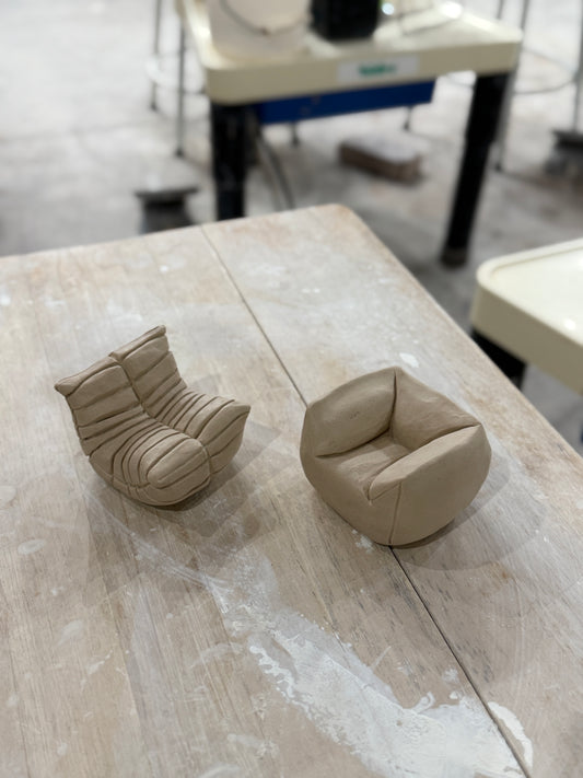 Two sofas made of clay sit on a wooden table