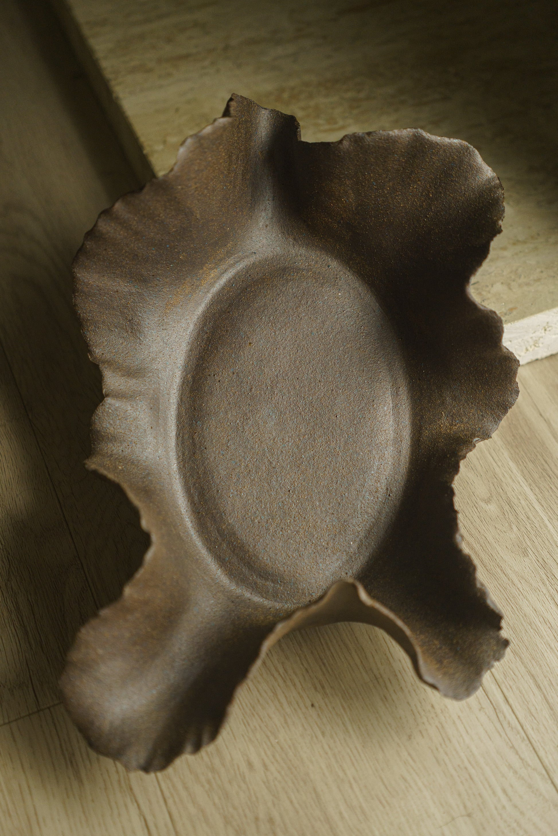 Large brown ceramic bowl, bare clay, with wavy ridges as rim