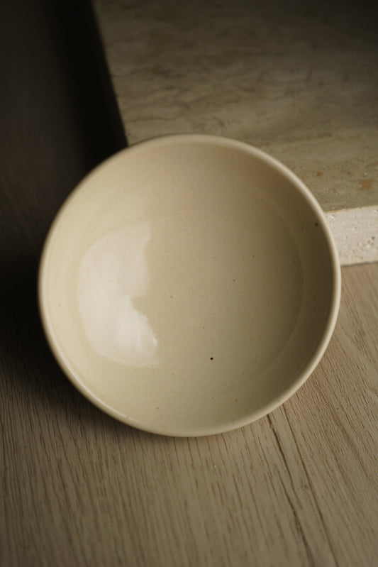 Beige ceramic bowl on a wooden surface