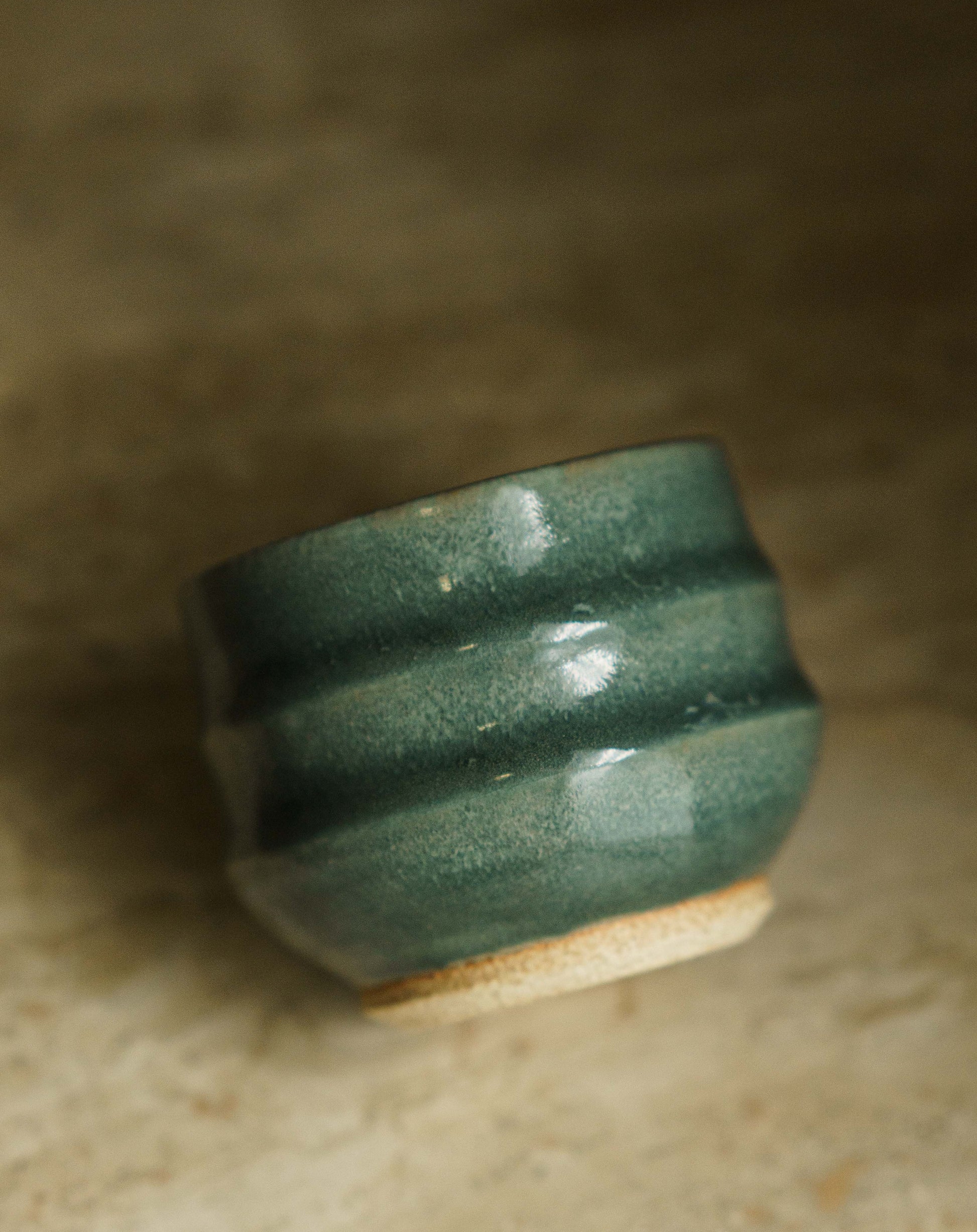 Small cup with two larger ridges in a turquoise glaze.