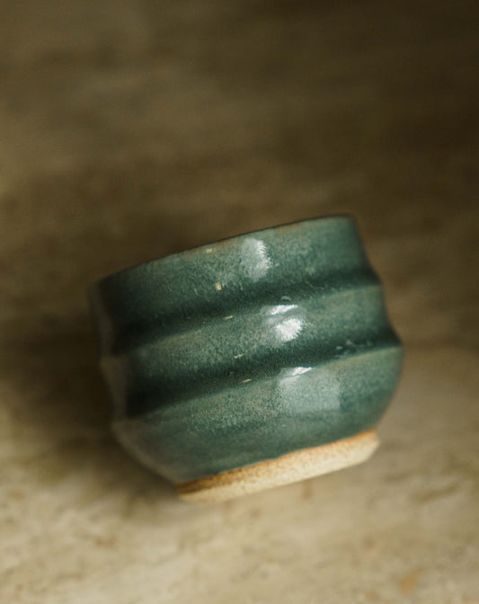 Small cup with two larger ridges in a turquoise glaze.