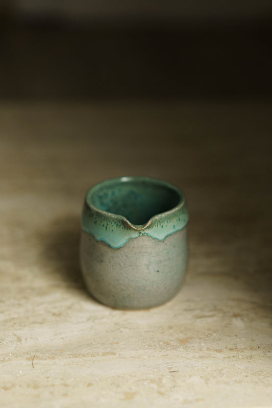 Small spouted beaker in a transparent glaze with light blue/green glaze inside and on the rim.