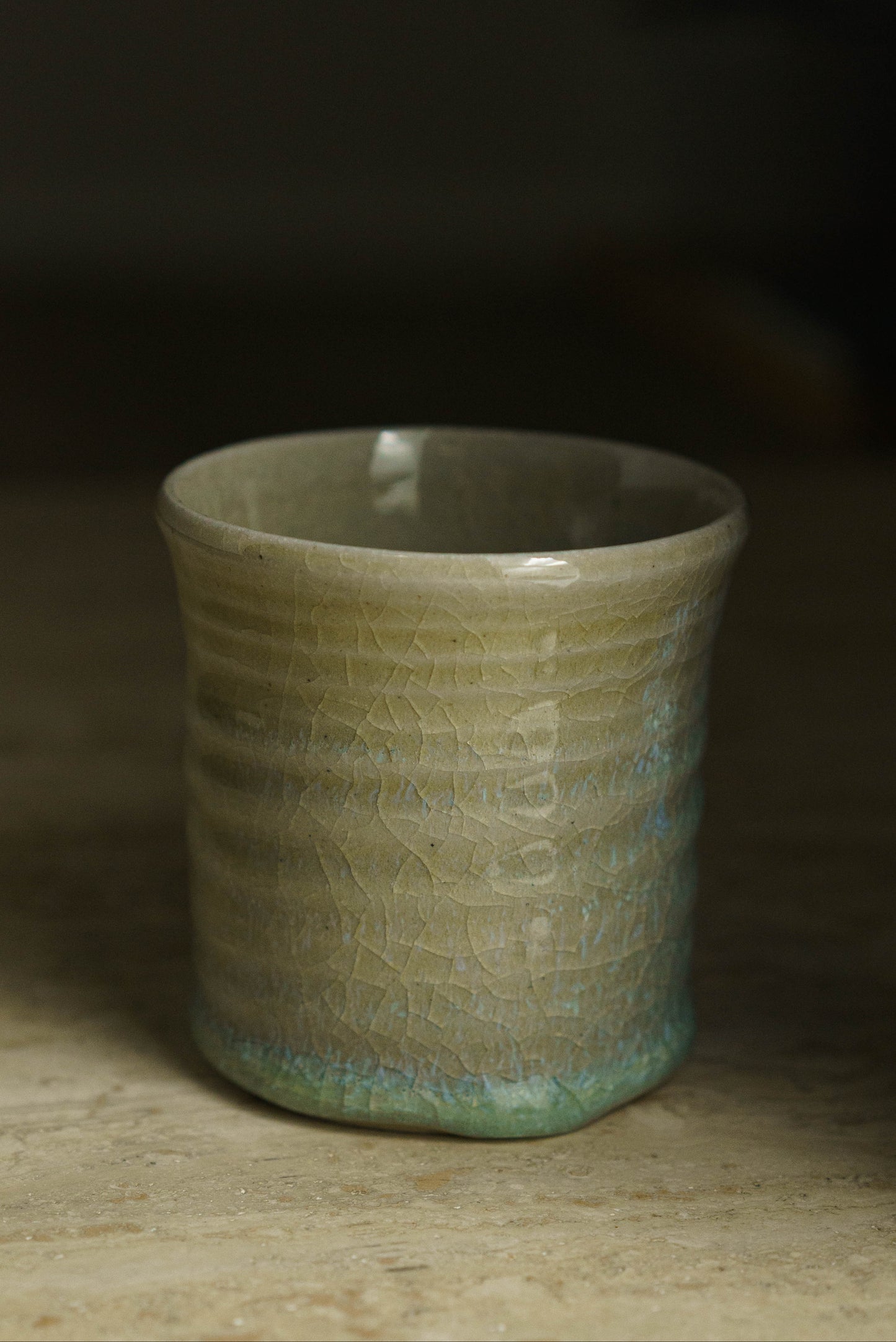 Sandy colored cup with small swirly ridges. Tinged faintly with blue and green throughout with more on the bottom.
