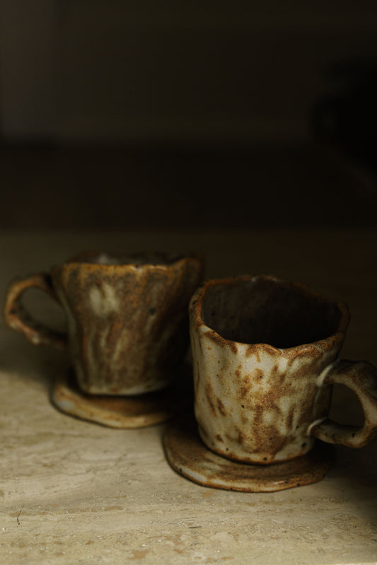 Two cups and two sauces, a mix of brown and white glaze covering.