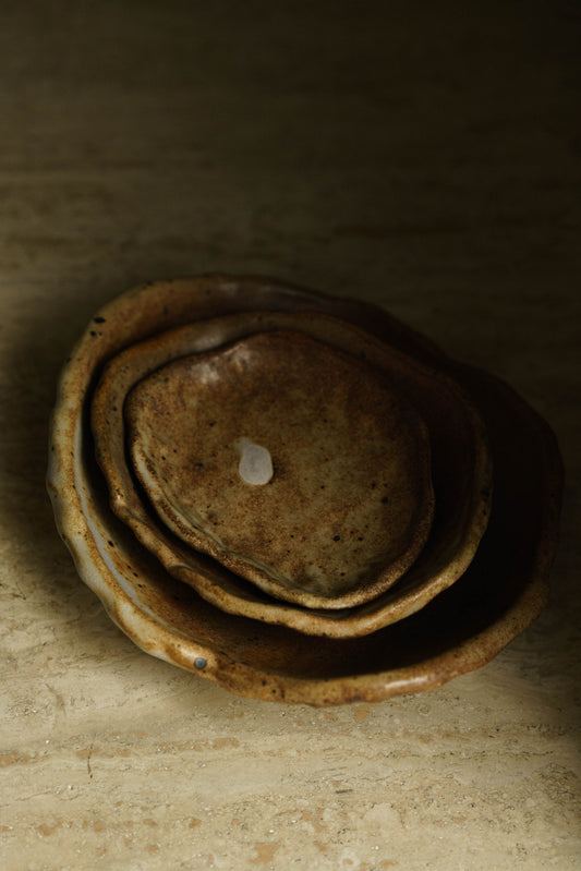 Three stacking catchall dishes in brown with some white areas.