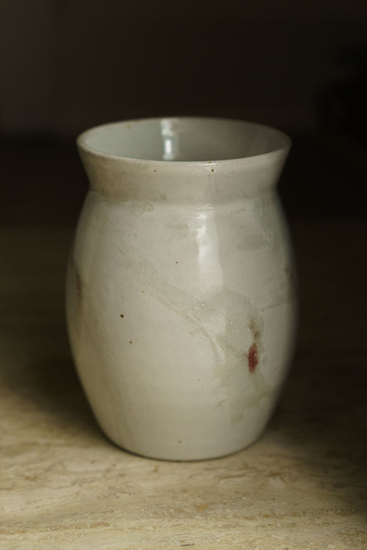 Large vase with rounded body and small angular lip. White glaze with transparent spatter and some tinges of red.