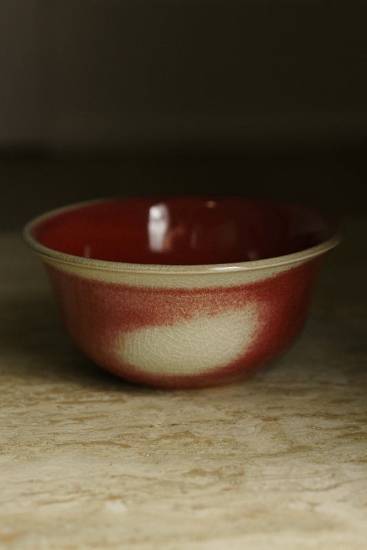 Lipped bowl in red with white patches.