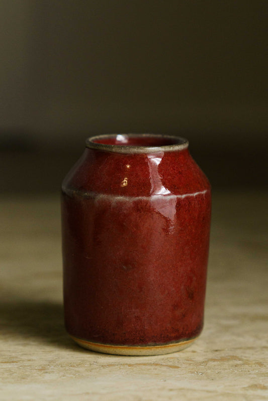 Small angular vase in red with white along the angle and rim.