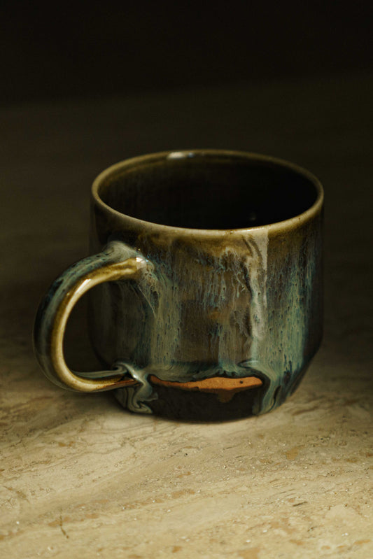 Ceramic mug with dark background glaze and tendrils of blue and white