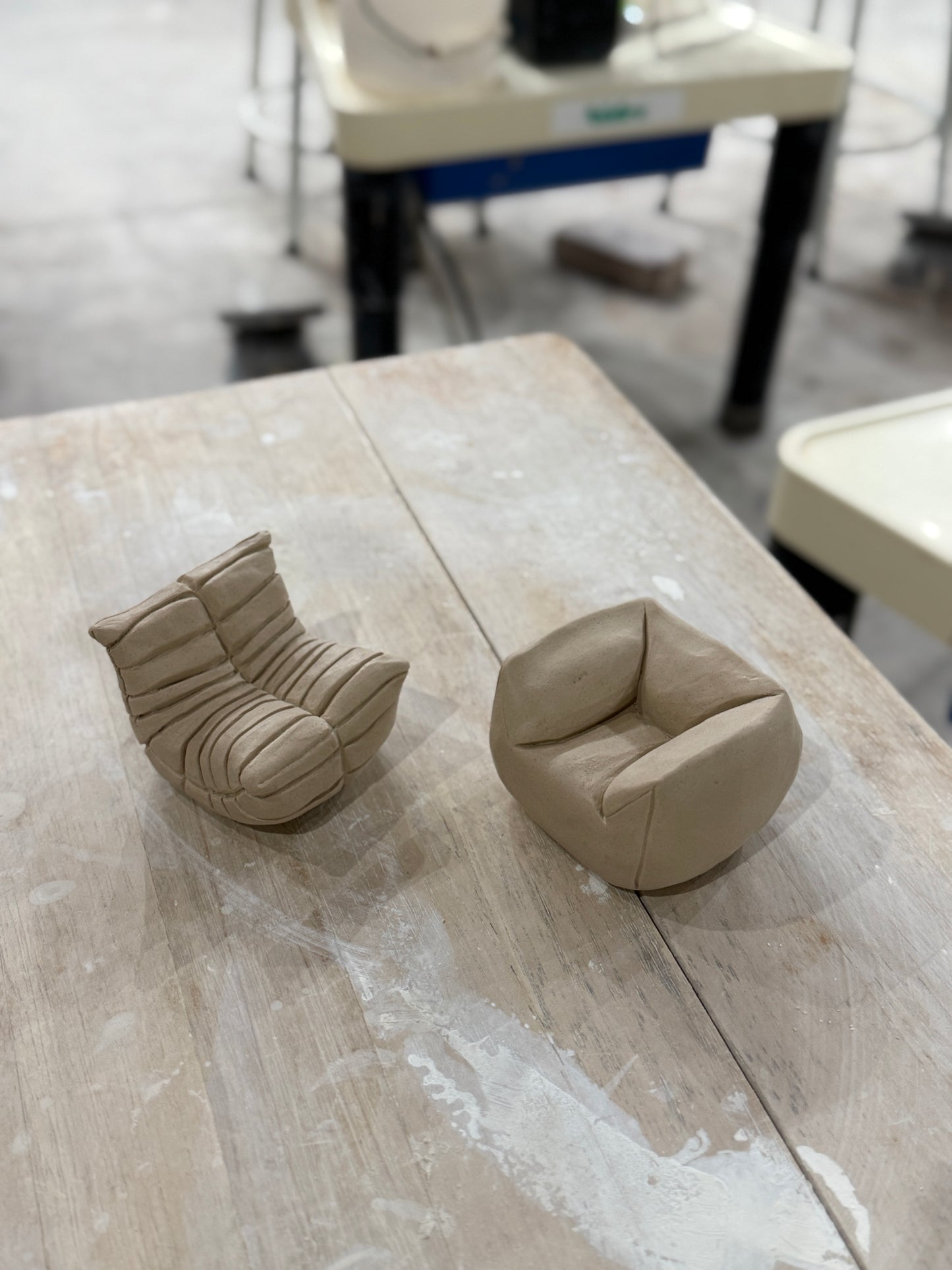 Two sofas made of clay sit on a wooden table