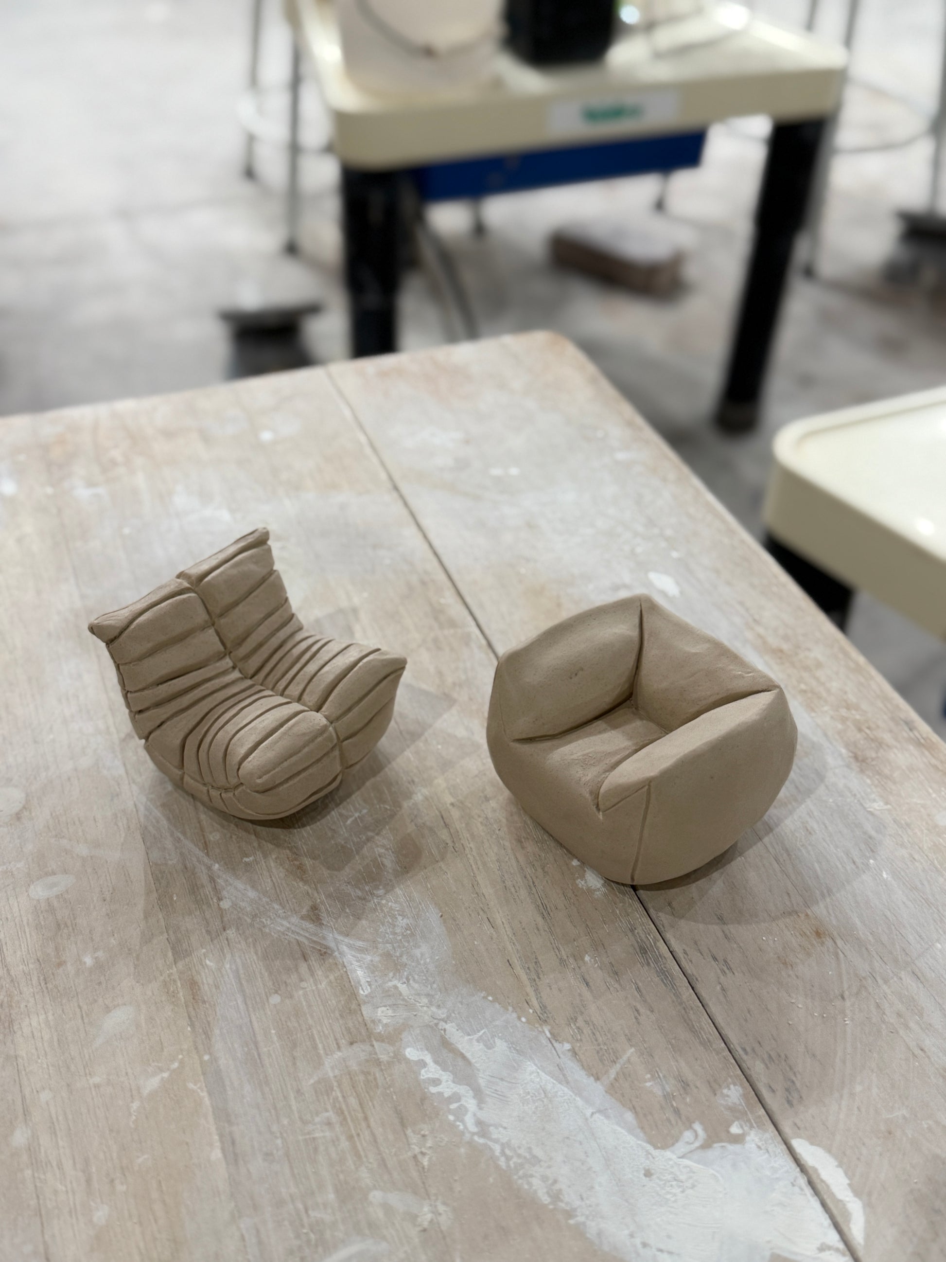 Two sofas made of clay sit on a wooden table